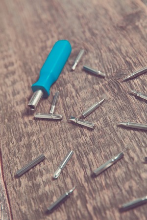 Blue screwdriver near sets of bits on wooden background.の写真素材