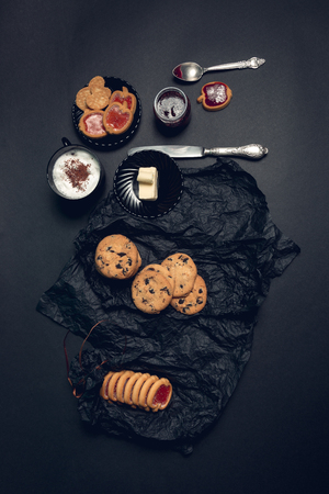 Cup of coffee, cappuccino with chocolate cookies and biscuits on black table background. Afternoon break time.の写真素材