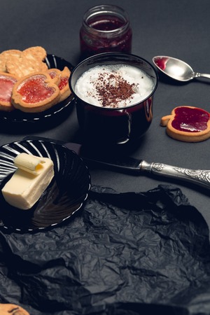 Cup of coffee, cappuccino with chocolate cookies and biscuits on black table background. Afternoon break time.の写真素材