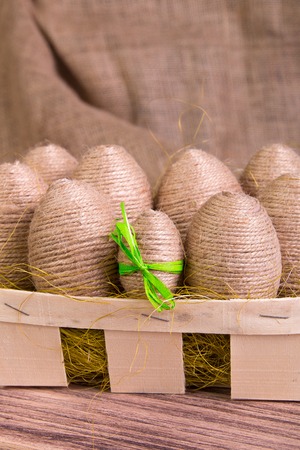 Easter eggs wrapped in twine in yellow nest on wooden sackcloth wooden background. Rusticの写真素材