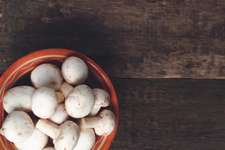 Fresh white mushrooms champignon in brown bowl on wooden background.の写真素材