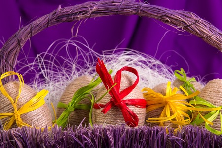 Easter egg decorative in twine in purple basket on wooden table on purpleの写真素材