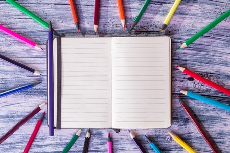 Color pencils near note on wooden background. Top viewの写真素材