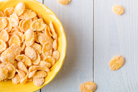 Healthy breakfast with cereal flakes on white background. Yellow tone. Top view