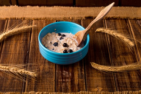 Oatmeal with currant in blue bowl with spoon on wooden background. Rustic style. Healthy breakfast. Close upの写真素材
