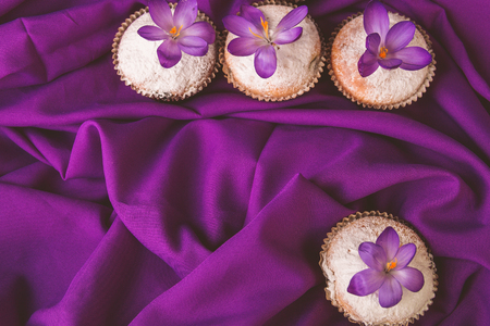 Muffins decorated with crocus flower on purple background.Spring. Top view. Copy spaceの写真素材