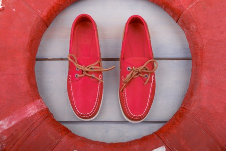 Red boat shoes on wooden background near lifebuoy. Top view. Close upの写真素材