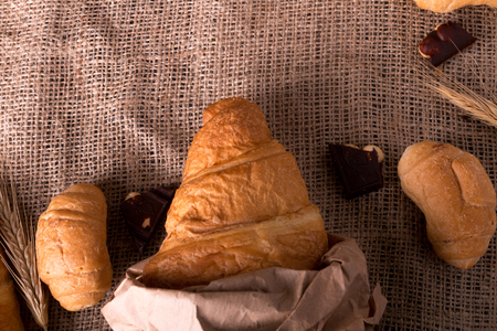 Croissants with chocolate on board near wheat on sackcloth background. Rustic style. Top viewの写真素材