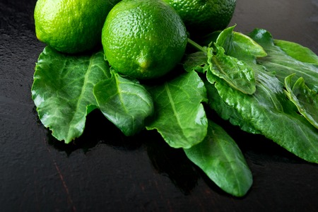Wet spinach and lime on black background. Green fruit. Detox. Fresh