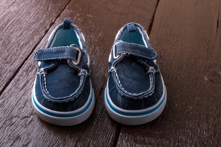 Blue boat shoes on brown wooden background. Boy footwear.の写真素材