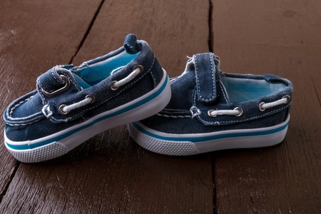 Blue boat shoes on brown wooden background. Boy footwear.の写真素材