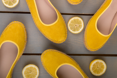 Yellow espadrilles shoes near slices of lemon on wooden background. Top viewの写真素材