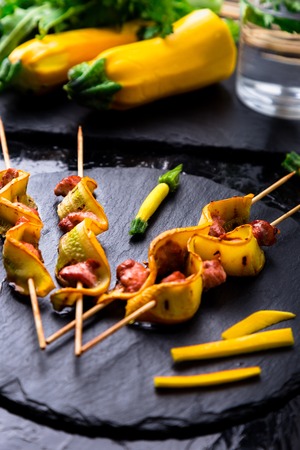 Yellow zucchini and chicken kebab on wooden stick on black stone slate plate. Close upの写真素材