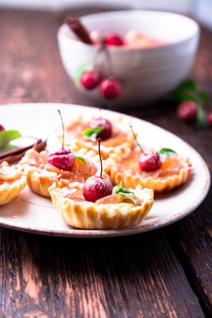 Apple caramel little tarts on white plate and brown rustic background. French tatin with paradise appleの写真素材