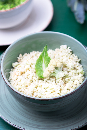 Cauliflower rice and broccoli rice in bowl on green background. Shreddedの写真素材