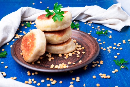 Towel of roasted pea patty in brown plate on blue wooden background. Top view