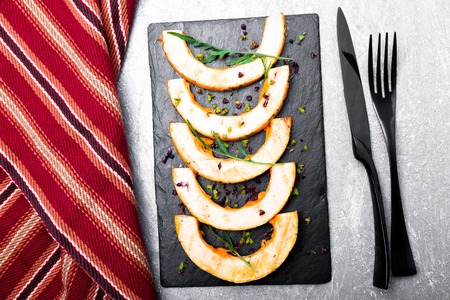 Grilled pumpkin on black slate plate on grey background.  Top view.の写真素材