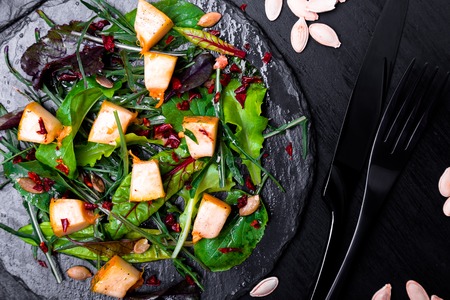 Warm pumpkin salad with mixed leaf of arugula, chard, in on black slate plate on black background. Grilled pumpkin. Top view.の写真素材