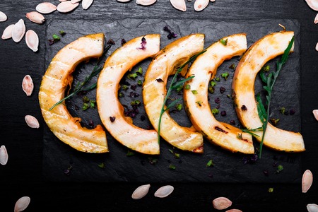 Grilled pumpkin on black slate plate on black background. Top viewの写真素材