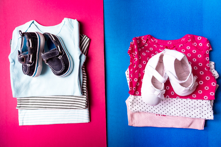 Folded blue and pink bodysuit with boat shoes on it on minimalistic pink and blue background. diaper for newborn boy and girl. Stack of infant clothing. Child outfit. Top viewの写真素材