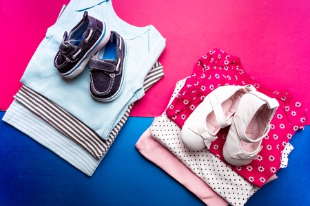 Folded blue and pink bodysuit with boat shoes on it on minimalistic pink and blue background. diaper for newborn boy and girl. Stack of infant clothing. Child outfit. Top viewの写真素材