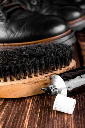 Black boots on wooden background with polishing equipment, brush and polish cream. Macro. Closeupの写真素材