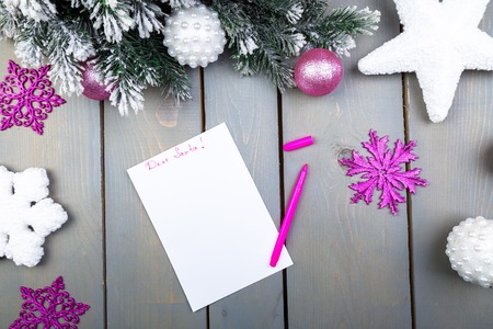 The sheet of paper, pink pencils and Christmas decorations on a wooden background. Concept of New year and Christmas. Top view. Flat lay.の写真素材