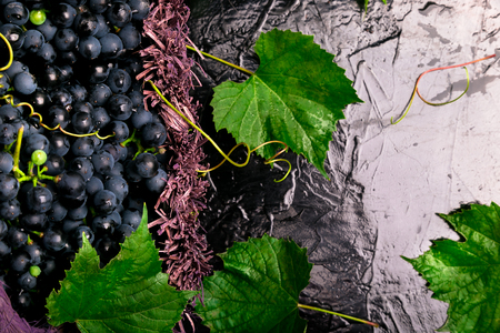 Red wine grapes in voiolet basket on bllack backgroundの写真素材