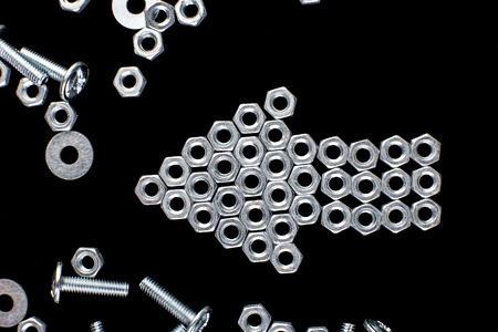 Arrow from metal nuts, bolts on black background. Flat layの写真素材