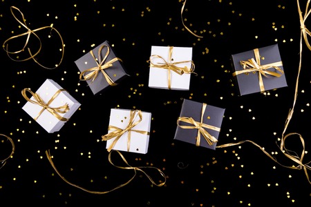 Black and white gift boxes with gold ribbon on shine background. Flat layの写真素材
