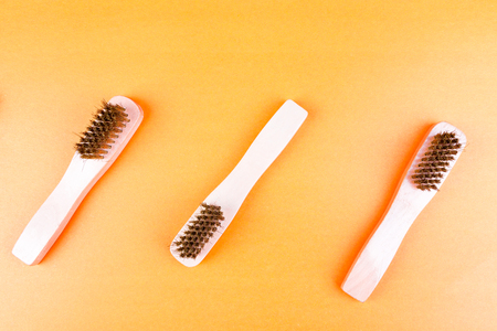 Three wooden suede brushes on yellow paper background