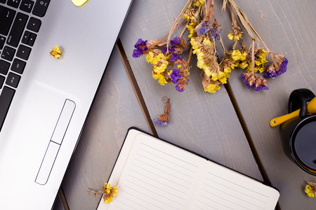 Notebook, coffee and flowers for female home or office workplace on wooden background. top view. Copy space.の写真素材