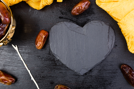 Dry fruit dates in golden cup near slate black heart. Copy space.Valentine Dayの写真素材