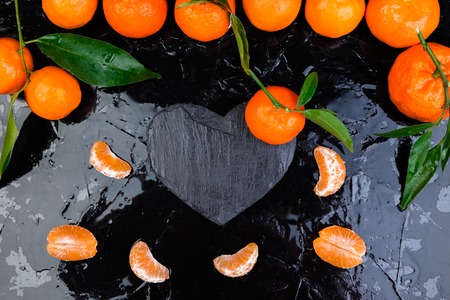 Tangerine around with black slate heart shaped. Frame. Copy space. Valentine Day.の写真素材