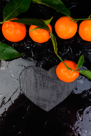 Tangerine around with black slate heart shaped. Frame. Copy space. Valentine Day.の写真素材