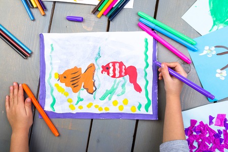 Child drawing. Top view of child hands with pencil painting picture on paper. Kid drawingsの写真素材