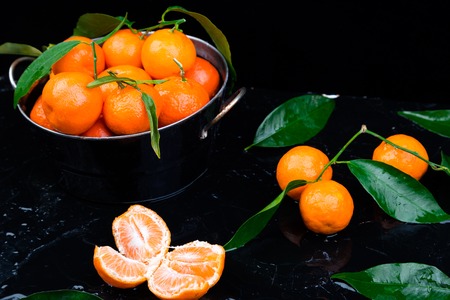 Fresh tangerines in the basket. Peeled sliced Tangerine orange and on a Black Background. Citrus background.の写真素材