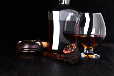 Glass of whiskey with smoking cigar on dark wooden tableの写真素材