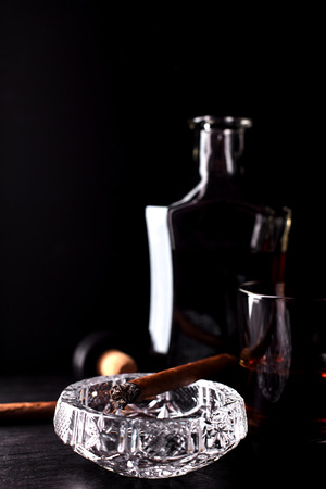 Glass of whiskey with smoking cigar on dark wooden tableの写真素材