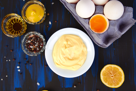 Homemade sauce Mayonnaise and ingredients eggs, oil,  lemon, mustar on dark blue background. Top view
の写真素材
