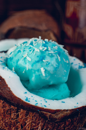 Blue ice cream in coconut bowl near sand, seashells, starfish. Close up.の写真素材