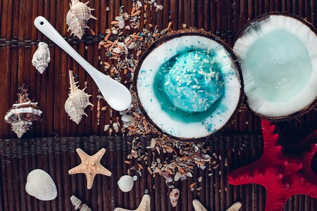 Blue ice cream in coconut bowl near sand, seashells, starfish.の写真素材