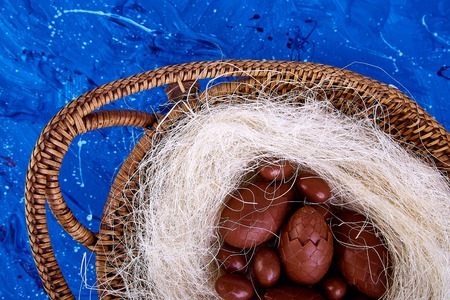 Chocolate easter egg in nest on blue background. Greeting card. Happy Easter. Spring. Copy space.の写真素材