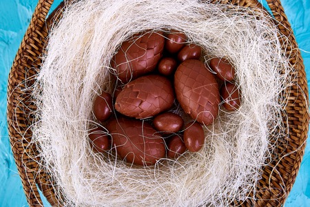 Chocolate easter egg in nest on blue background. Greeting card. Happy Easter. Spring. Copy space.