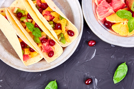 Fruit tacos with orange, kiwi, grapefruit on  dark background and berry. Summer snacks. Top view. Copy space.
の写真素材