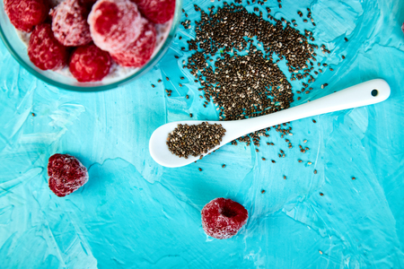 Healthy chia pudding with raspberries in glass on blue background. Vegan creamy breakfast. Detox and healthy superfoods breakfast concept.の写真素材