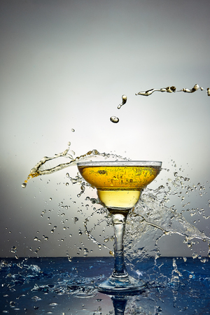 Glass with yellow champagne or alcohol drink cocktail, martini glasses. Pouring. Splash. Levitationの写真素材