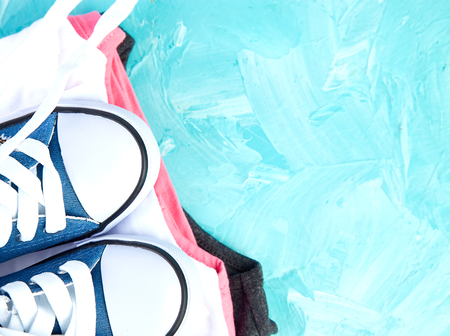 Flat lay of female sneakers shoes and tee on a blue background. Copy space. Top view. Spring or summer outfit. Fashion. Woman or Girl Accessories.の写真素材