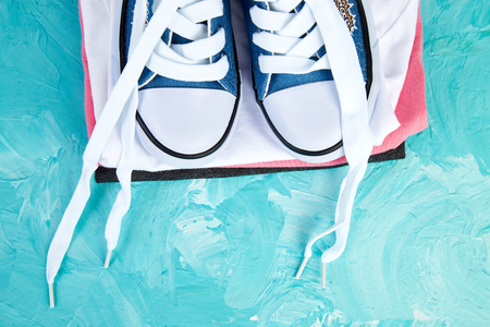 Flat lay of female sneakers shoes and tee on a blue background. Copy space. Top view. Spring or summer outfit. Fashion. Woman or Girl Accessories.の写真素材