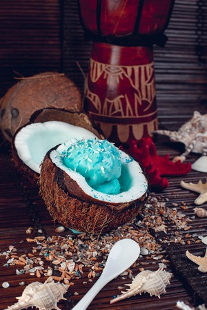 Blue ice cream in coconut bowl near sand, seashells, starfish. Summer vacationの写真素材